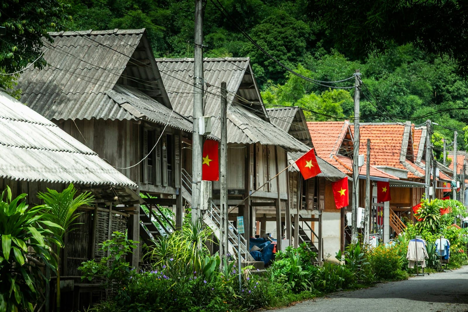 Dãy nhà sàn gỗ cắm cờ đỏ dọc con đường trong bản ở Mai Châu